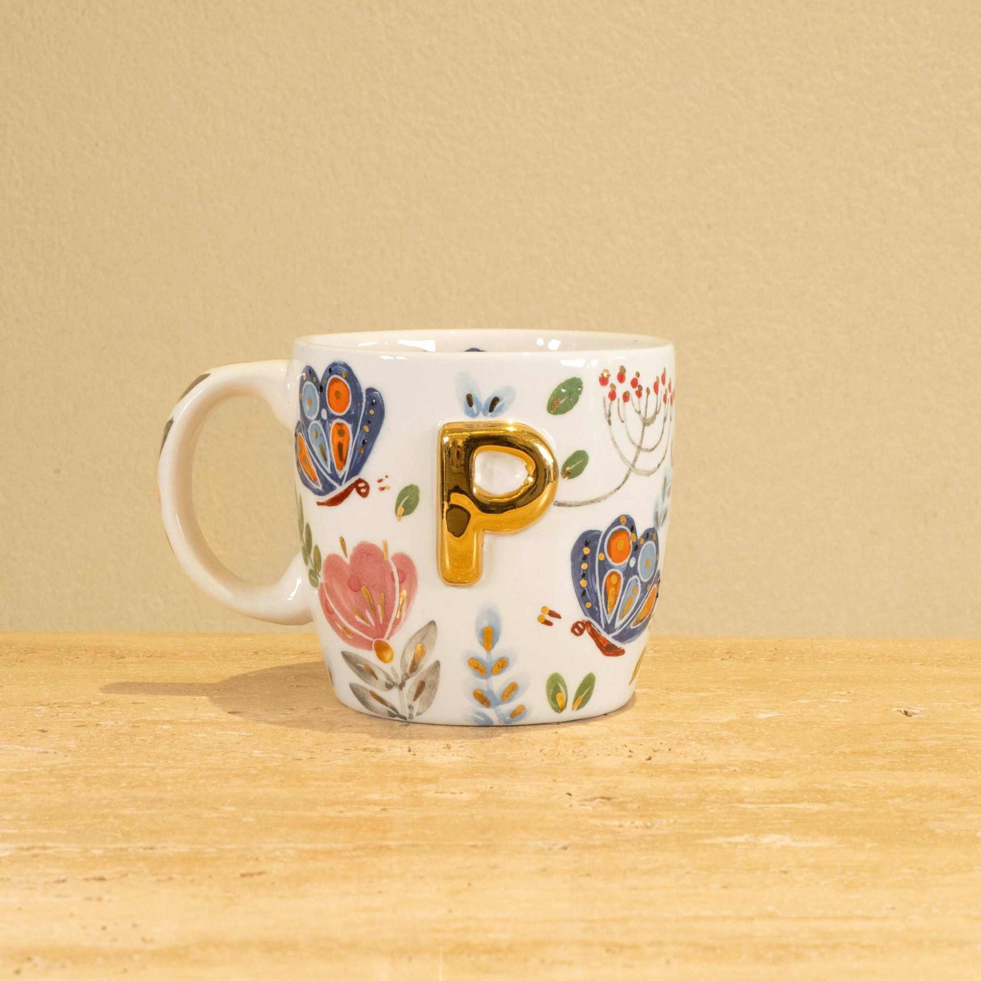 Custom handmade ceramic mug with gold-plated initial "P" and floral design.