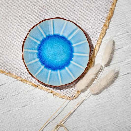 ACEM Ceramic Tea Plate in blue with sunburst design and textured center on woven placemat.