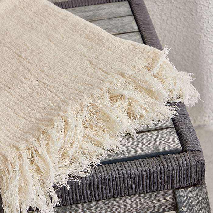CHANEL BOUNCLE throw blanket in beige on a wooden chair.