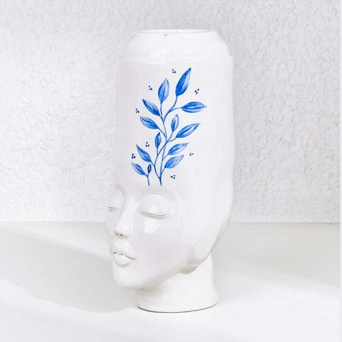 Ceramic handmade girl face pot with blue leaf design.