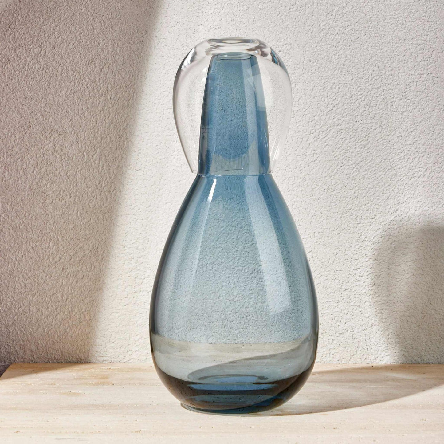 Steel blue night water set with a hand-blown glass carafe and matching tumbler lid, on a wooden surface.