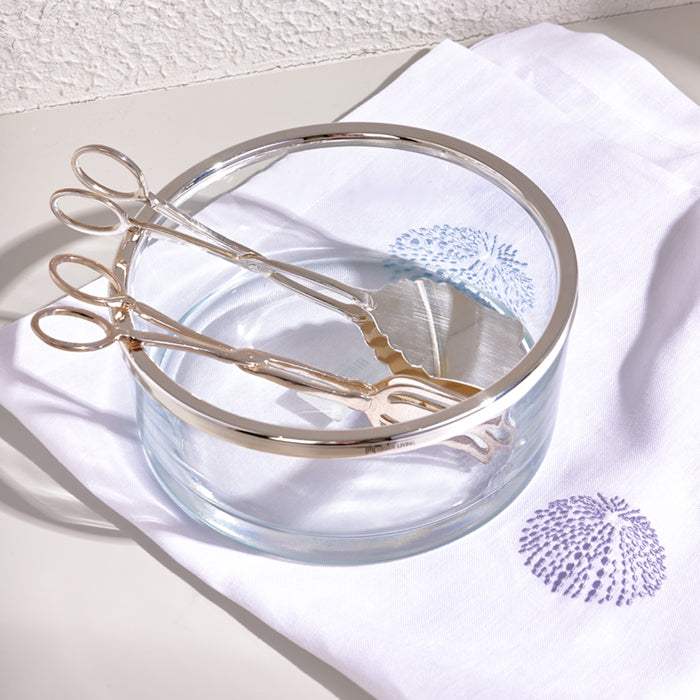 Sleek silver salad tong set with polished finish in a clear glass bowl.