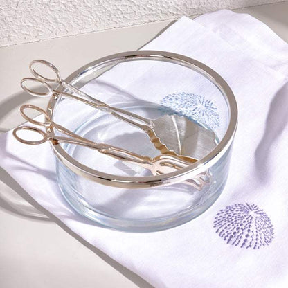 Sleek silver salad tong set with polished finish in a clear glass bowl.